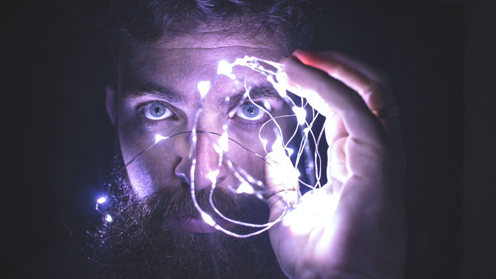 man looking through eerie lights he's holding up in front of his eye -- meant to convey a brain implant for the internet